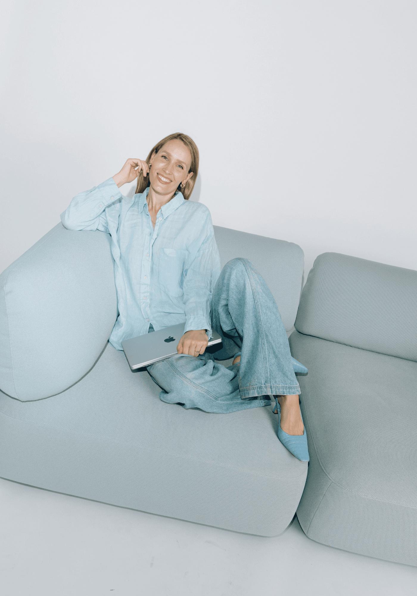Stella Maria Sorg, Gründerin von CMO Studios und Expertin für KI im Marketing, sitzt mit Laptop auf einem Sofa